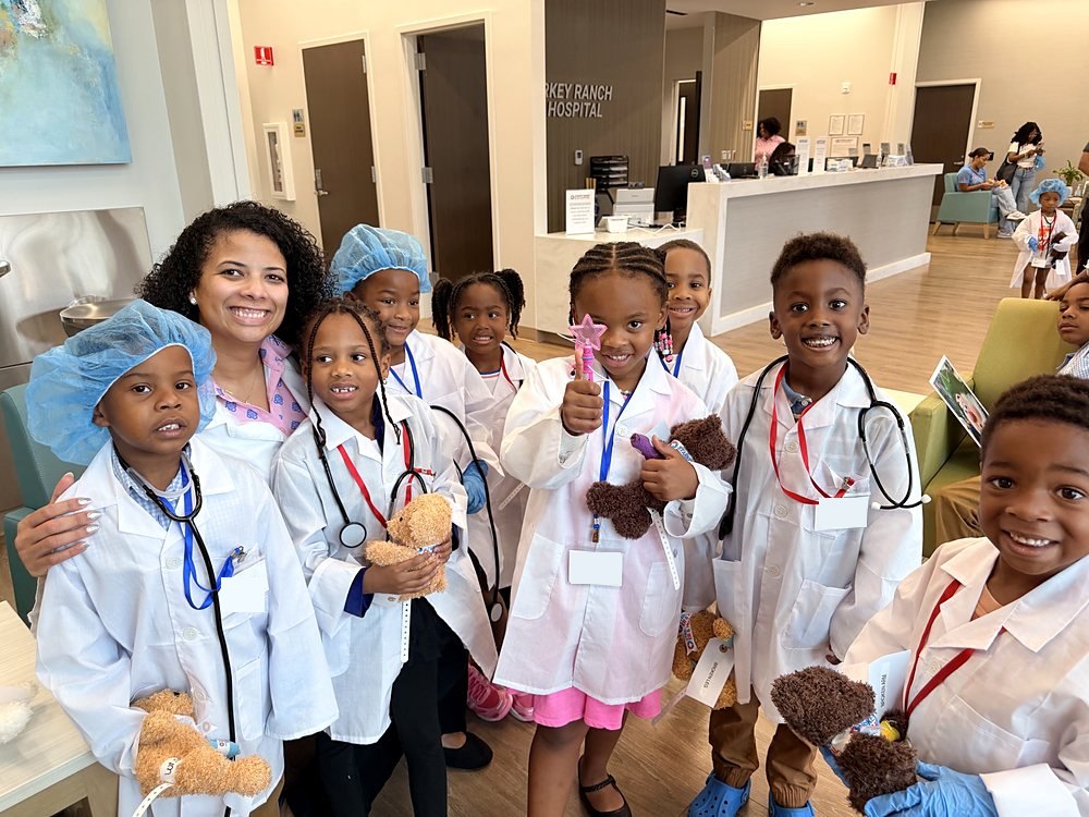 Young children in doctor coats at a hospital career visit